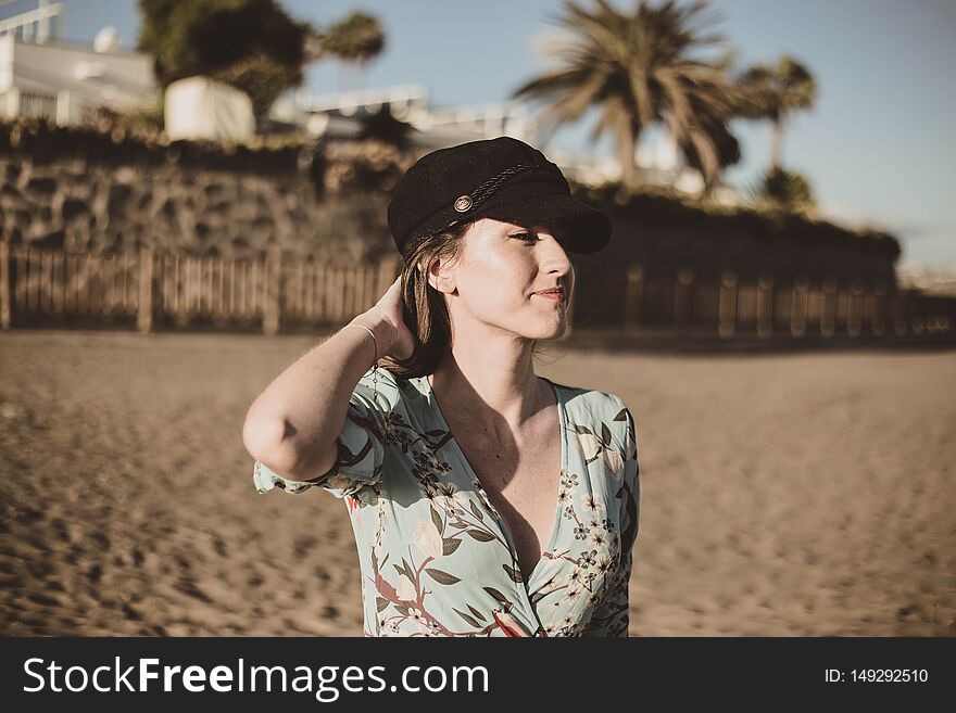 Beautiful young woman portrait in the desert touching her hair with a black cap