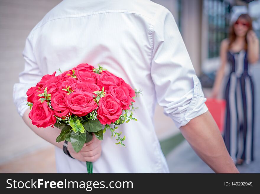 Man holding red roses in the hands for surprise his girlfriend, couple concept, valentine`s day concept