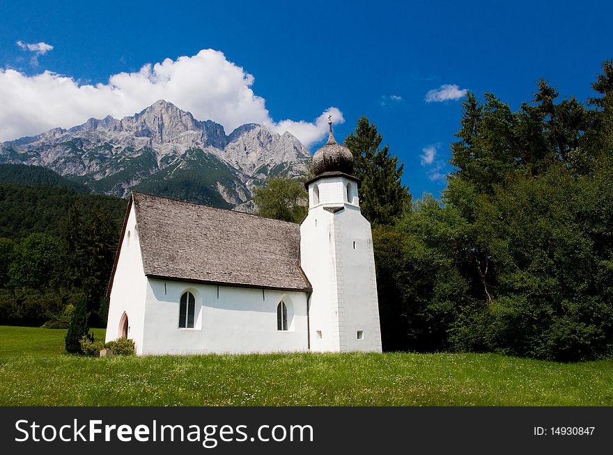 Small white church underneath the alpine peaks. Small white church underneath the alpine peaks