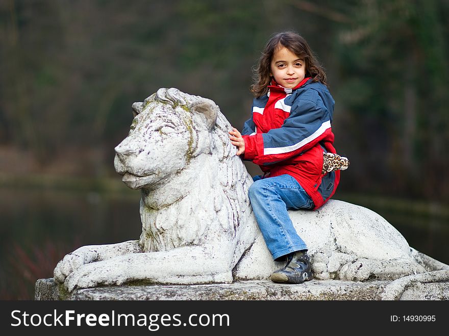 Young girl riding on back of stone lion