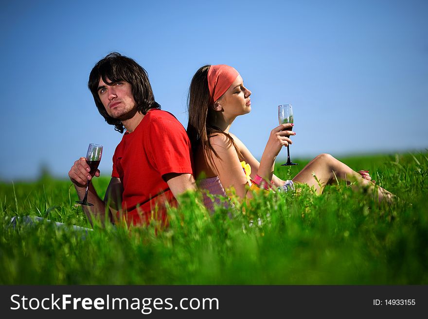 Nice girl in kerchief and boy with wineglasses on grass. Nice girl in kerchief and boy with wineglasses on grass