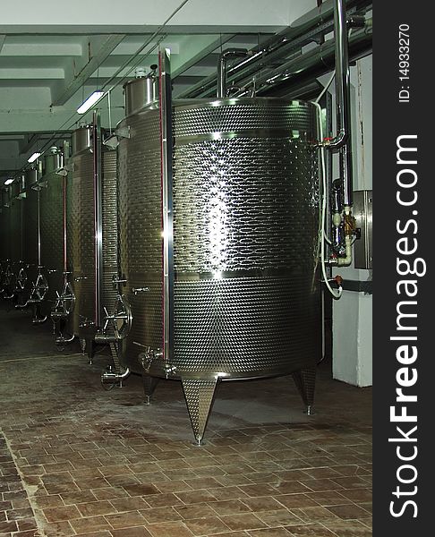 Wine factory - metal barrel of wine. Wine Fermenting in huge vats in a wine cellar.