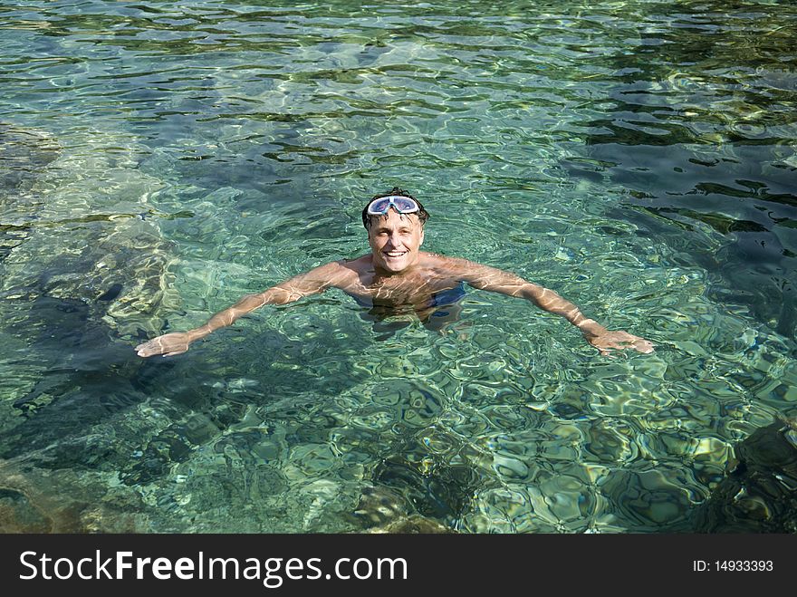 A color portrait photo of a happy smiling forties man relaxing in the clear blue water during his summer vacation. A color portrait photo of a happy smiling forties man relaxing in the clear blue water during his summer vacation.