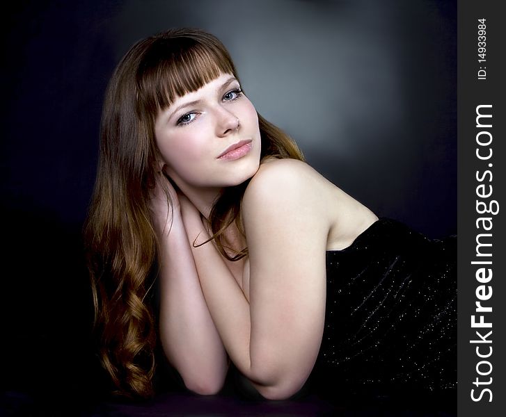 Beautiful brunette girl posing in studio on dark background