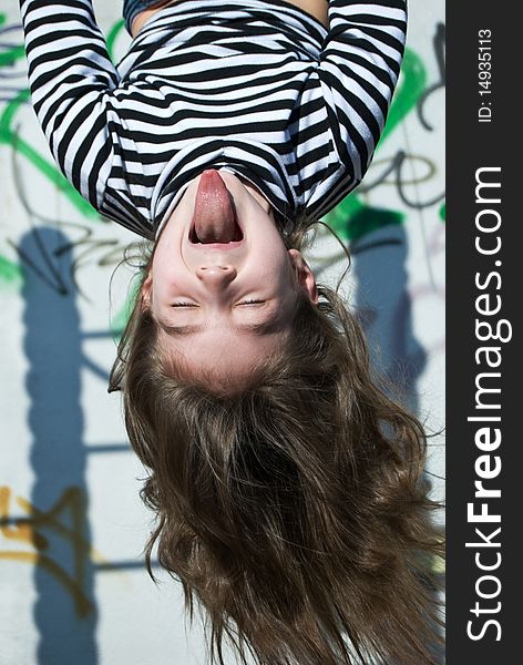 A cute little girl in a sailor's striped vest doing exercises and putting tongue out. A cute little girl in a sailor's striped vest doing exercises and putting tongue out