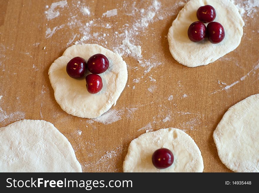 Raw dumplings with fresh red cherries on the table