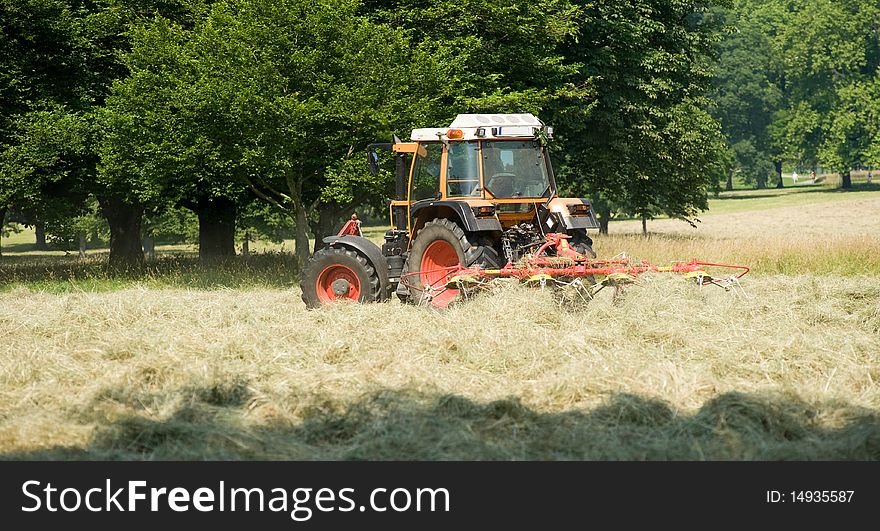 Tractor with hay turning equipment on the meadow