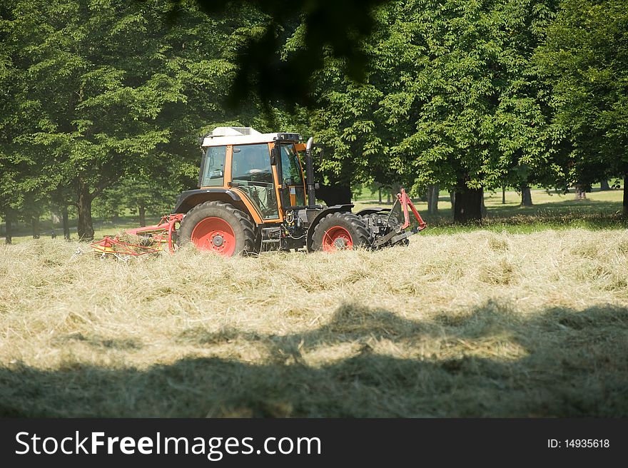 Tractor with hay turning equipment on the meadow. Tractor with hay turning equipment on the meadow