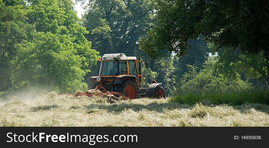 Tractor with hay turning equipment on the meadow. Tractor with hay turning equipment on the meadow