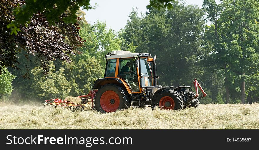 Tractor with hay turning equipment on the meadow. Tractor with hay turning equipment on the meadow