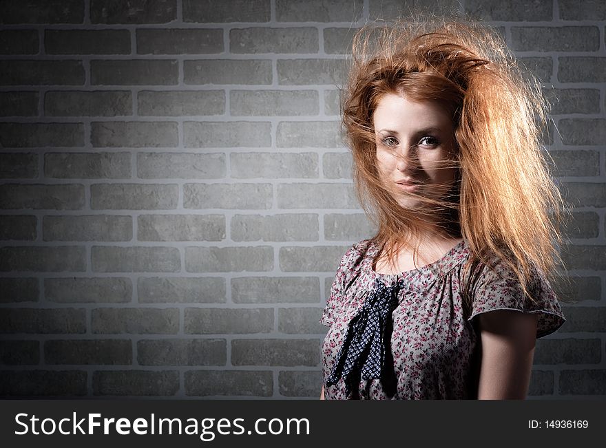 Redhaired mysterious woman against brick wall .