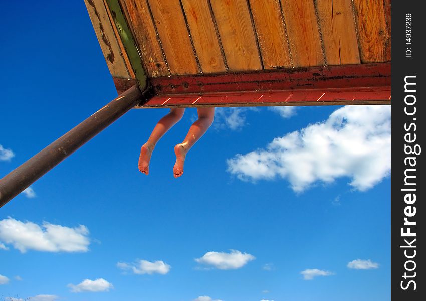 Teenagers legs hanging down on the blue sky background