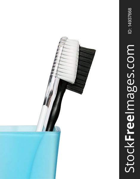 Black and white toothbrushes in blue glass. Isolated with clipping path. Black and white toothbrushes in blue glass. Isolated with clipping path