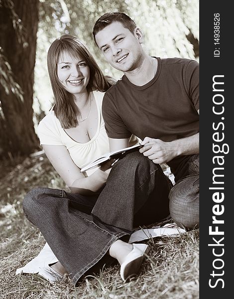 Young happy couple reading a book outdoors