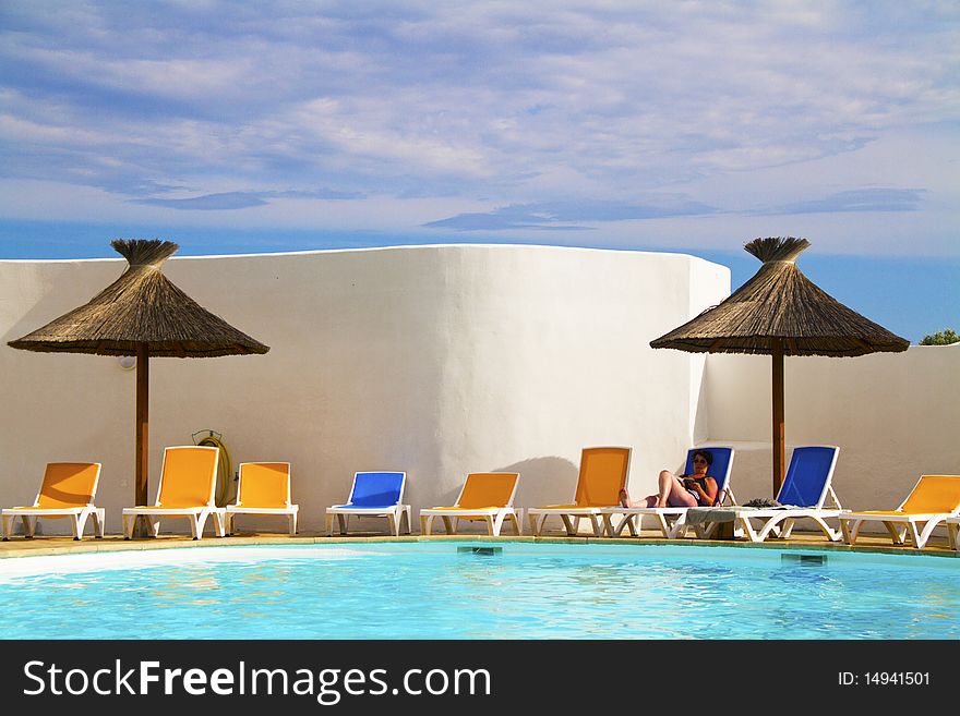 Swimming pool with lounge chairs and thatched umbrellas. Swimming pool with lounge chairs and thatched umbrellas