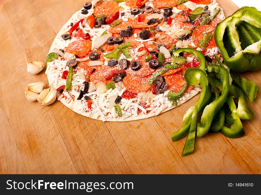Raw pizza with pepperoni, bell peppers, black olives and onions. Raw pizza with pepperoni, bell peppers, black olives and onions