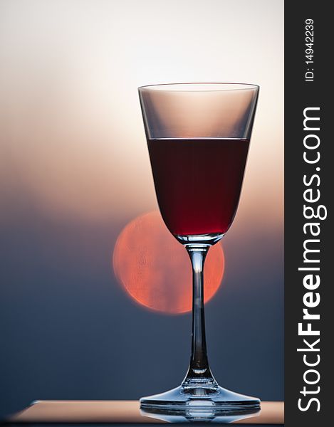 Closeup of a glass of wine with setting sun in background. Closeup of a glass of wine with setting sun in background