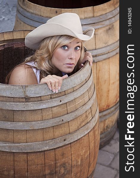 Young cowgirl peeking out of a barrel with a worried look on her face. Young cowgirl peeking out of a barrel with a worried look on her face.