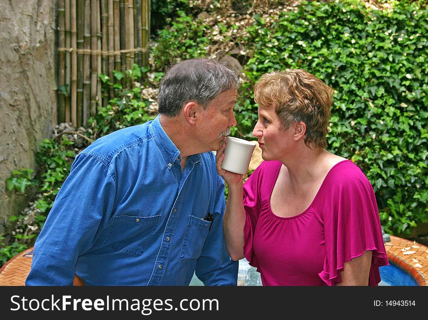 A middle-aged couple flirting over a cup of coffee. A middle-aged couple flirting over a cup of coffee