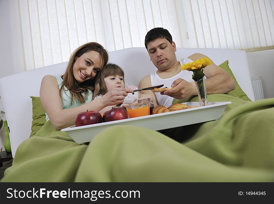 Happy young family eat breakfast in bed at morning