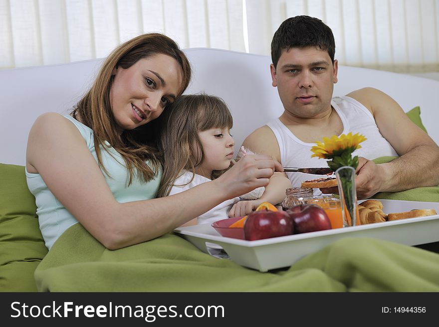 Happy young family eat breakfast in bed