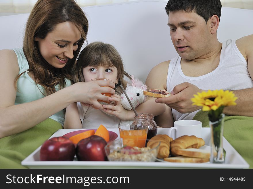Happy young family eat breakfast in bed at morning