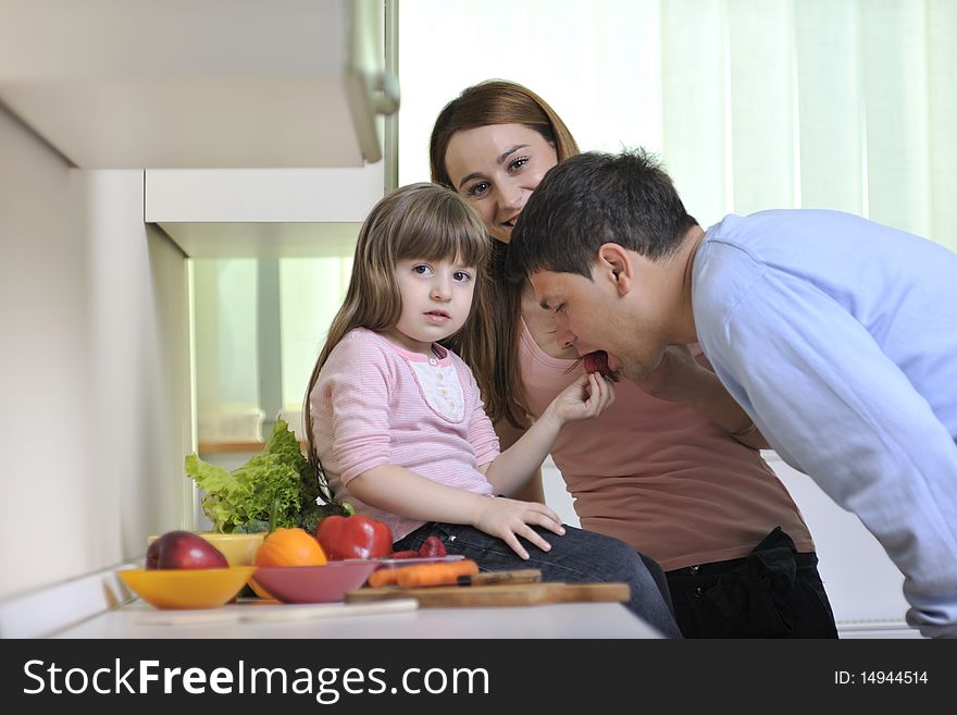 Happy young family have lunch time with fresh fruits and vegetable food in bright kitchen. Happy young family have lunch time with fresh fruits and vegetable food in bright kitchen
