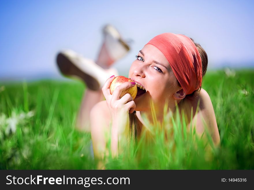 Nice girl in kerchief with apple on grass