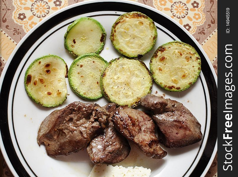 Slices of green and yellow Italian zucchini, pan fried and sprinkled with herbs. Served on white plate with black lining. Slices of green and yellow Italian zucchini, pan fried and sprinkled with herbs. Served on white plate with black lining.