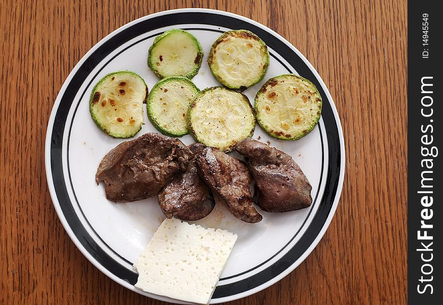 Slices of green and yellow Italian zucchini, pan fried and sprinkled with herbs. Served on white plate with chicken liver. Slices of green and yellow Italian zucchini, pan fried and sprinkled with herbs. Served on white plate with chicken liver.