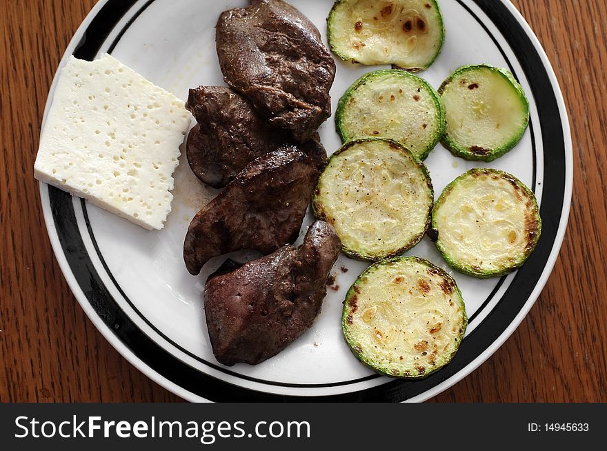 Slices of green and yellow Italian zucchini, pan fried and sprinkled with herbs. Served on white plate with chicken liver. Slices of green and yellow Italian zucchini, pan fried and sprinkled with herbs. Served on white plate with chicken liver.