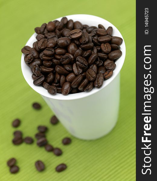 Coffee beans in a cup isolated against a green background