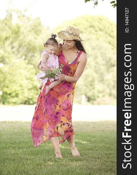 Mother holding her daughter while out for a walk in the park. Mother holding her daughter while out for a walk in the park