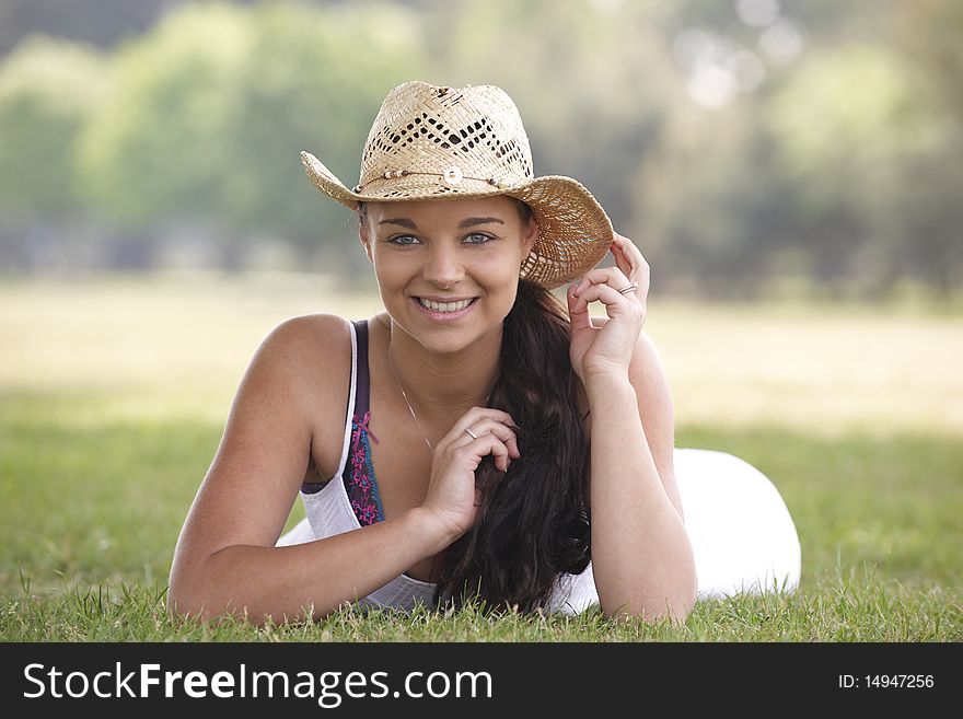 Young attractive girl lying on grass wearing a summer hat. Young attractive girl lying on grass wearing a summer hat
