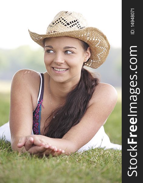Young attractive girl lying on grass wearing a summer hat. Young attractive girl lying on grass wearing a summer hat