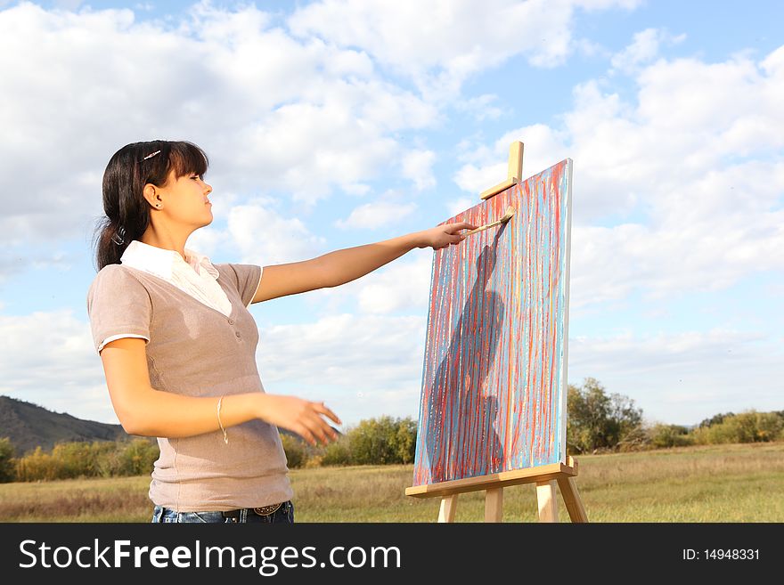 Woman painting on a background of a beautiful landscape. Woman painting on a background of a beautiful landscape