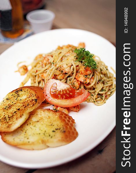 Close up of seafood spaghetti with tomato and garlic bread.