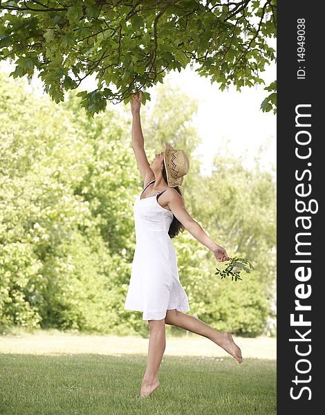 Young attractive woman stretching to reach leaves. Young attractive woman stretching to reach leaves