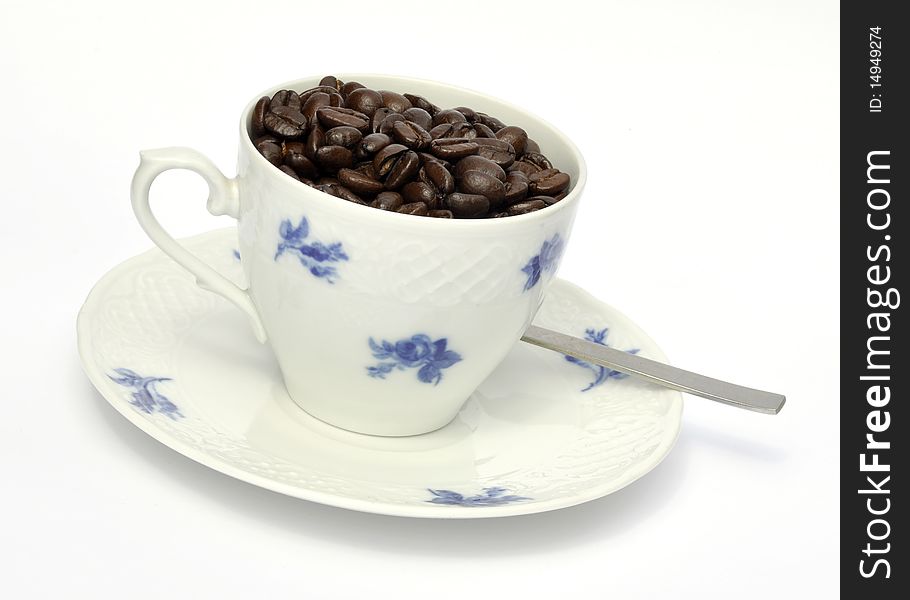 Roasted coffee beans fill china cup and saucer