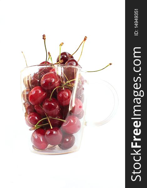 Ripe, darkly red sweet cherry in transparent  cup on a white background.