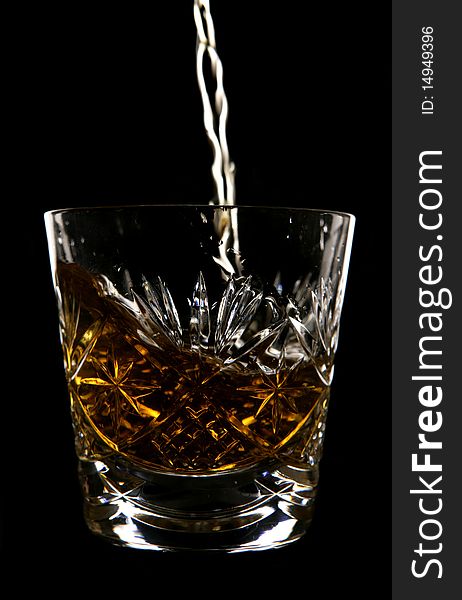 Whiskey being poured in crystal glass in studio