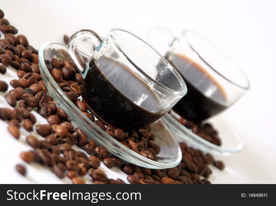 Two coffee cups made by transparent glass in diagonal with a lot of coffee beans. Two coffee cups made by transparent glass in diagonal with a lot of coffee beans