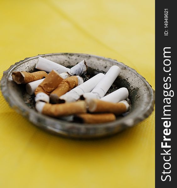 Cigarettes in ashtray on yellow background