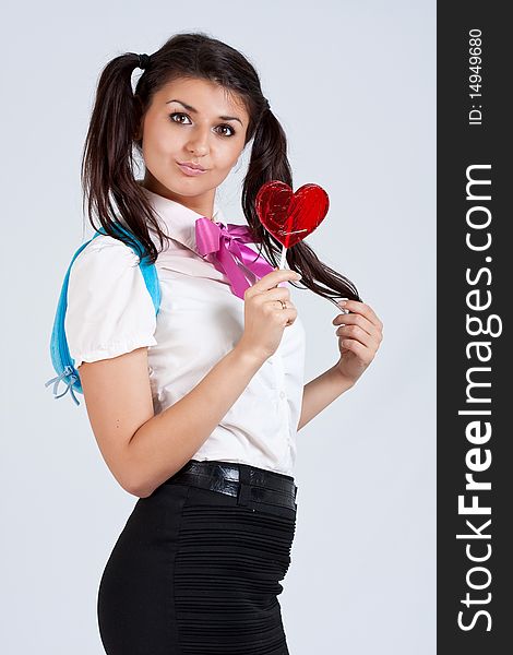 Cute schoolgirl with candy at studio