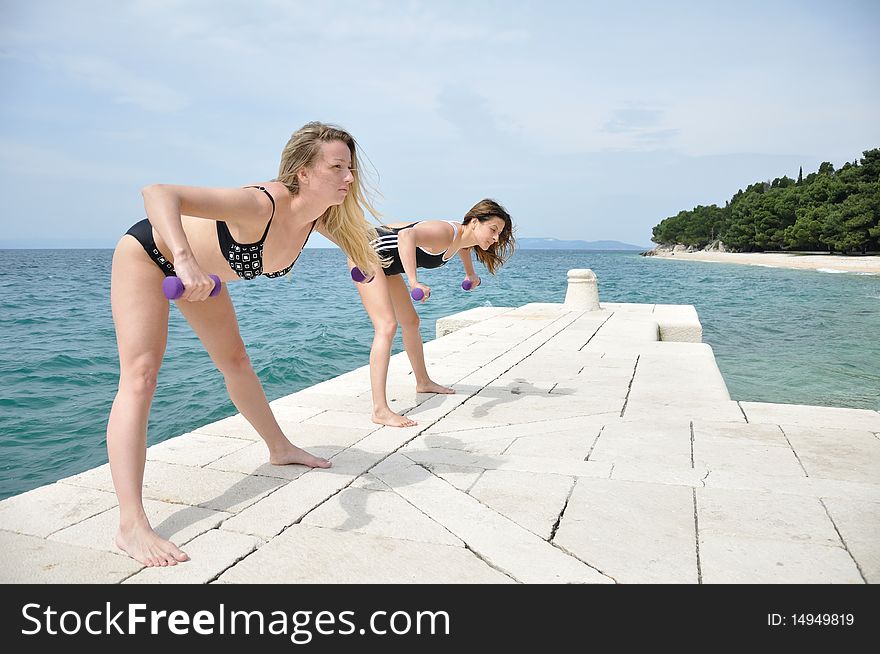 Young students lifting weights on the beach