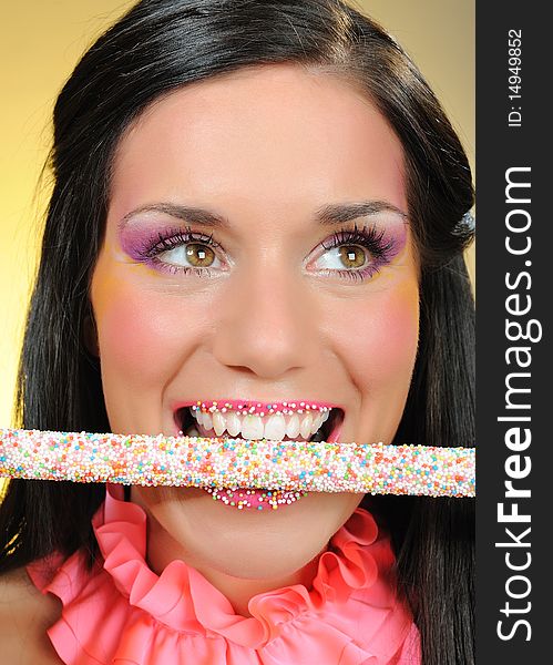 Beautiful happy girl with a sweet lollipop and creative makeup . yellow background