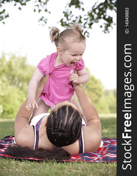 Mother playing with daughter in the park in summer