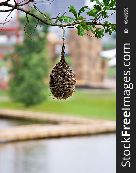 A bird house made of materals found in nature hanging in a tree.