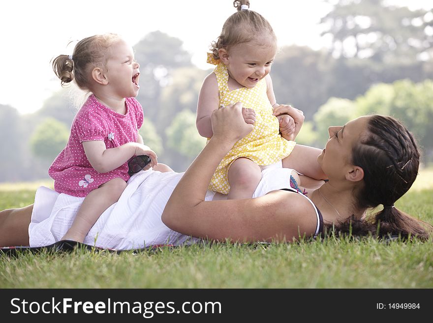 Mother playing with daughters in the park in summer