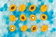 Cut Halves Of Ripe Apricots With Or Without Stones Against The Background Of Transparent And Blue Ice Cubes Royalty Free Stock Image